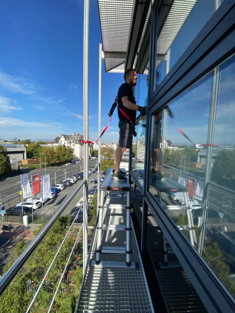 sonnenschutzfolie-pressehaus-offenbach-04-montage-mit-absturzsicherung Monteur mit Absturzsicherung bei der Folierung in den oberen Gebäudebereichen